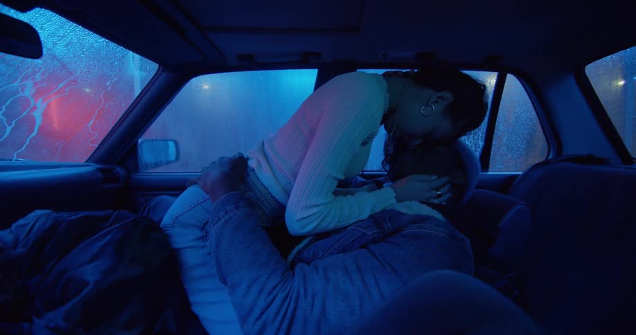 A man and a woman kissing in a car going through a car wash