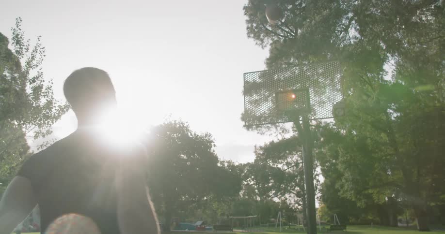 A young man shoots baskets outside
