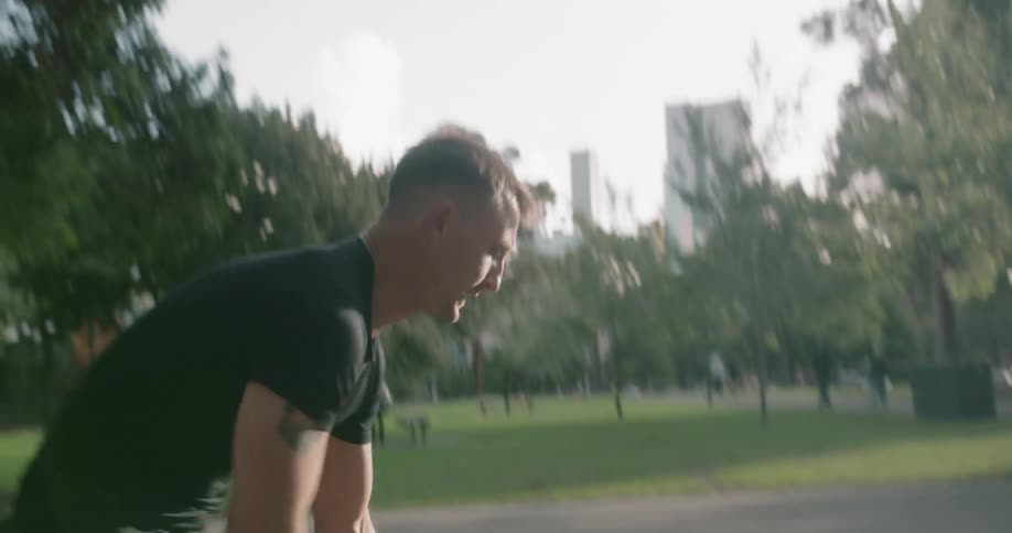 A muscled man dribbles a basketball on a court in a park