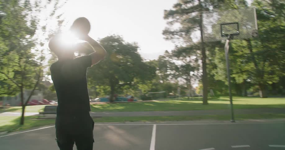 A white man shoots baskets outside