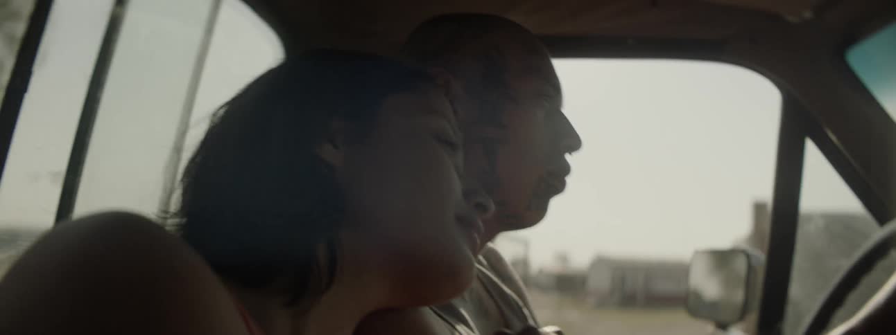 A man and woman hold hands while driving in a car