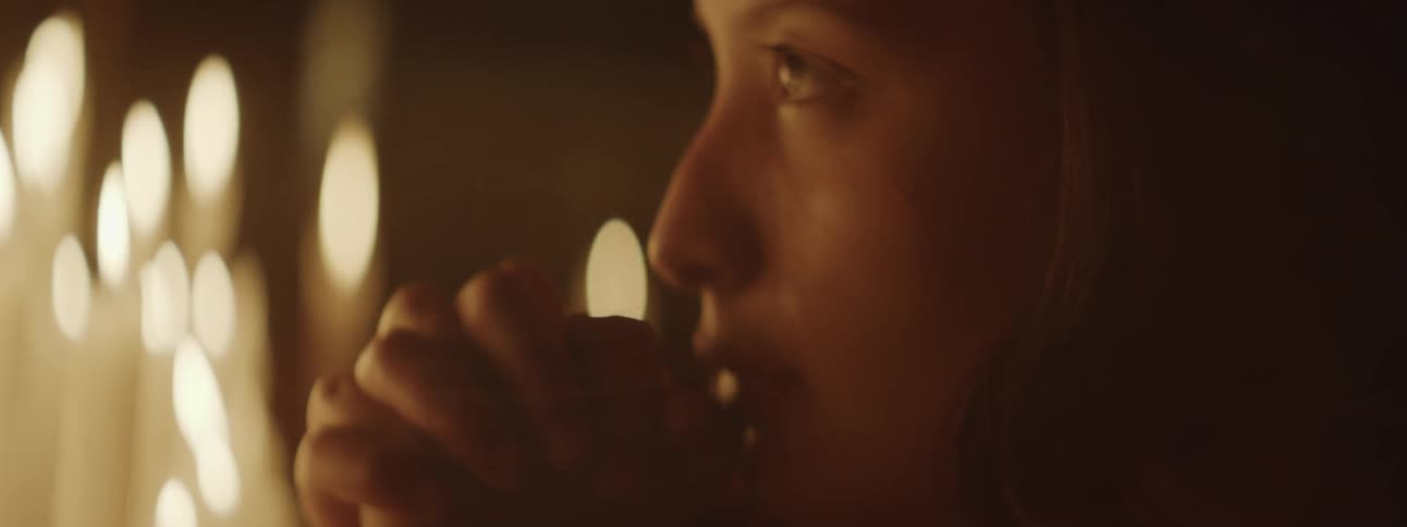 Concerned woman praying near candles at church