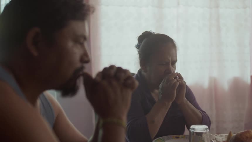 Man and woman praying at dinner table before eating