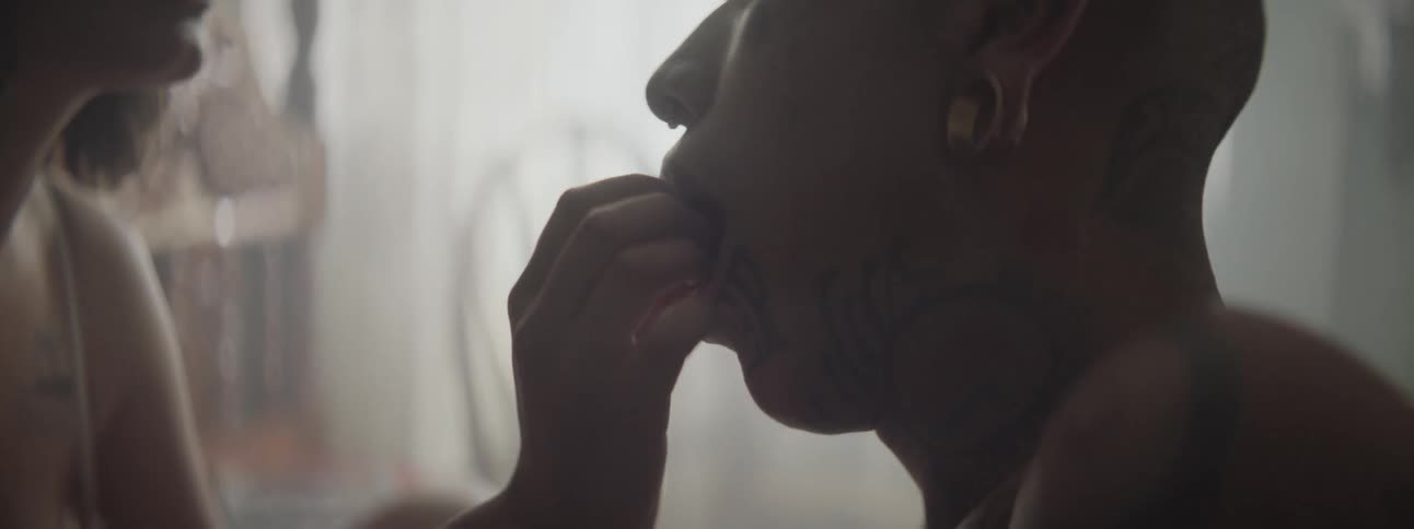 A woman places food in a mans mouth with her fingers as they sit face to face