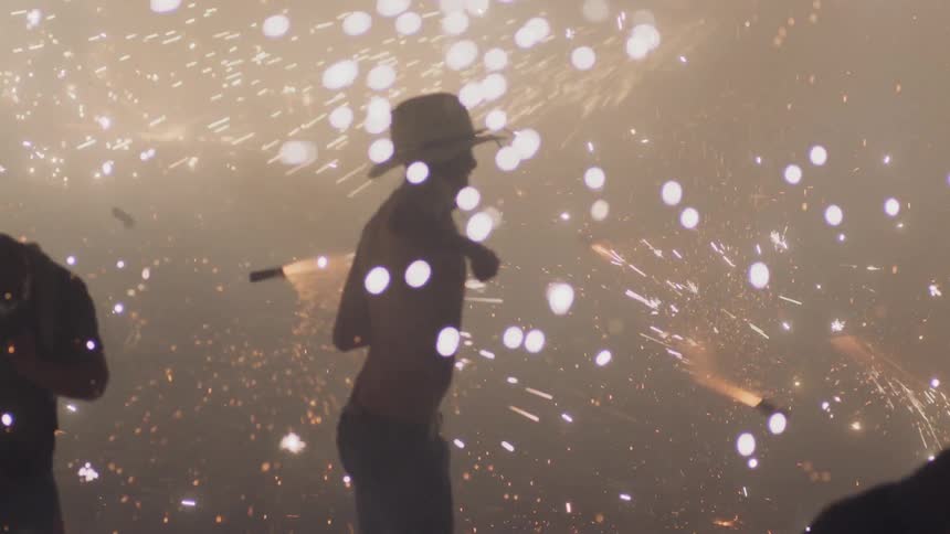 A shirtless man jumping around while works spin all around him