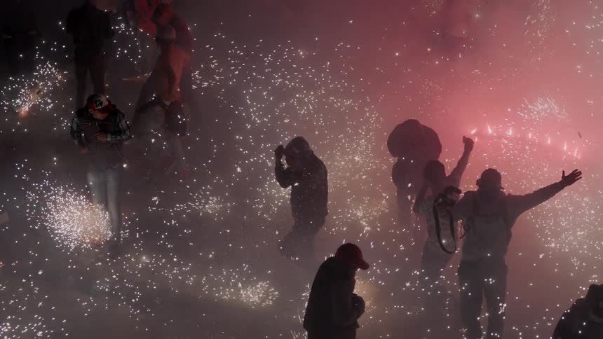 A large group of people run amongst countless small fireworks that spray sparks in all directions