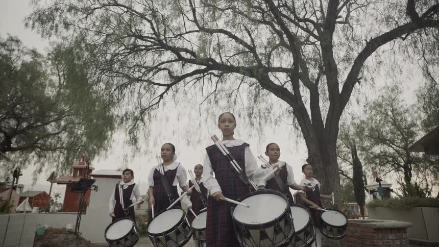 A group of girls in uniform beat on drums
