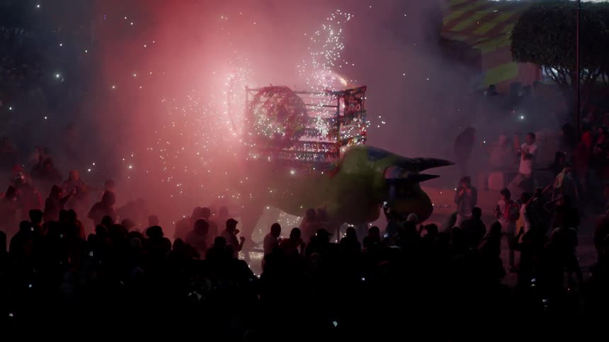 A firework display on a parade float surrounded by a large crowd