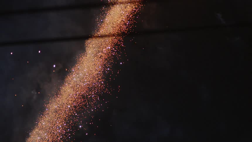 Sparkling fireworks are shot high into the dark nighttime sky leaving embers to fall downward