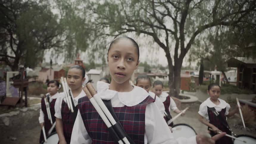 Young girls march along while playing the drums