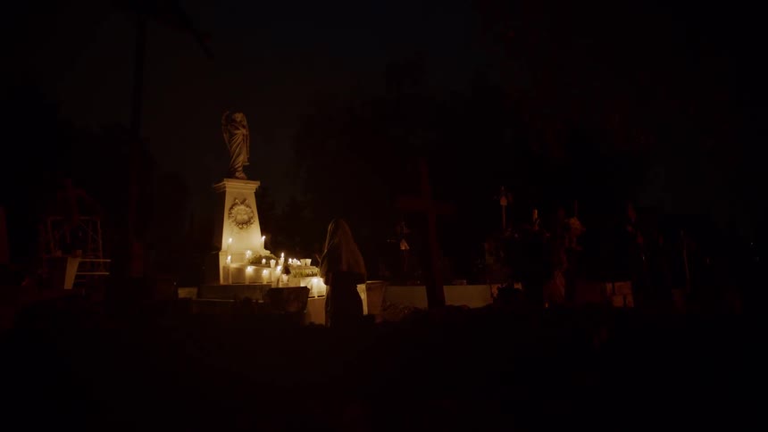 People stand at an altar covered in candles at night