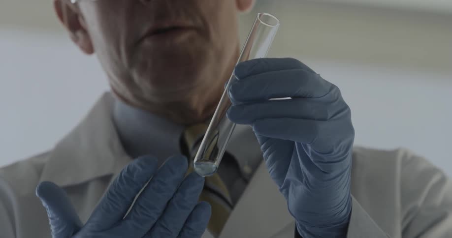 A chemist using a dropper to drop liquid into a vial