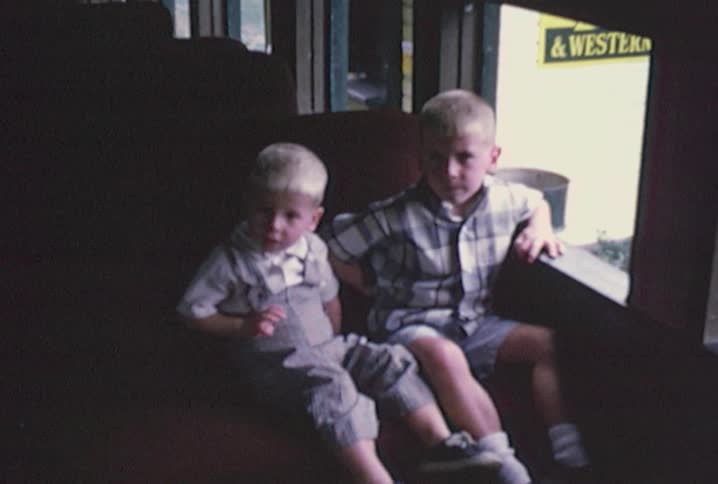 Two children are sitting in a train looking out the window