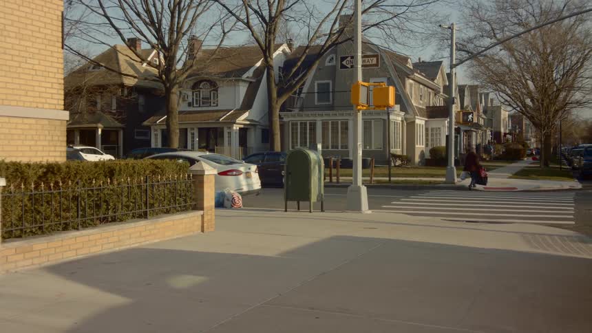 A person walks across the street at an intersection carrying bags