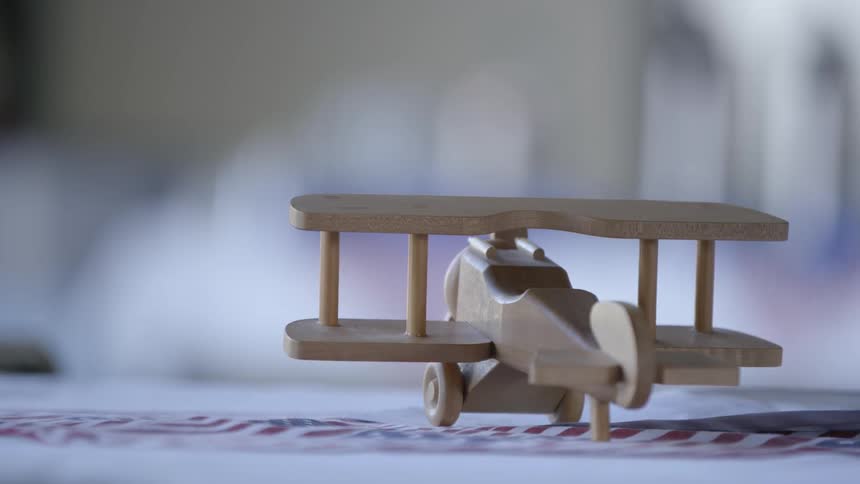 A toy wooden airplane sits on a table