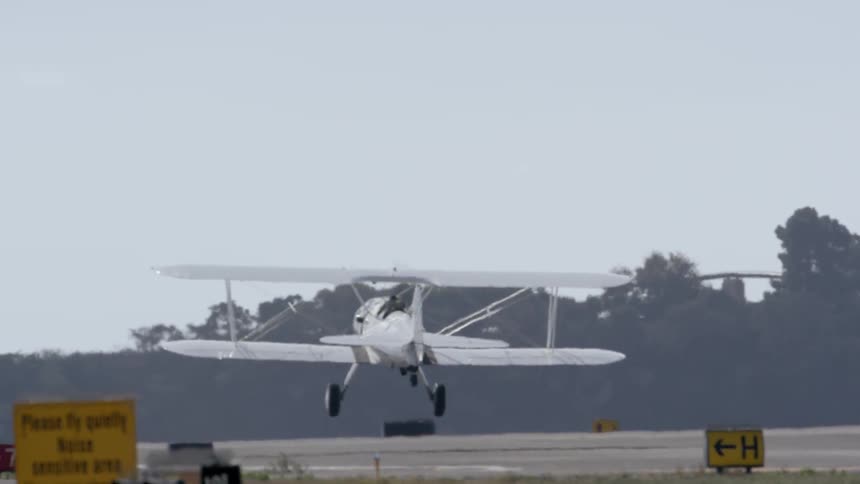 Biplane rolling down a runway and ascending into the air