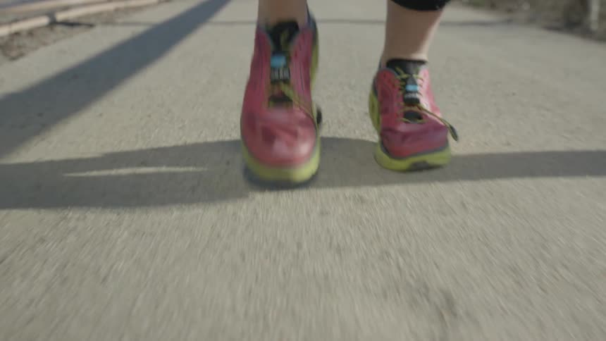 A woman's feet hit the ground as she jogs