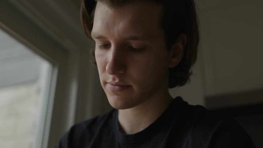 A caucasian man in a black shirt sitting indoors