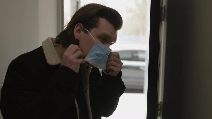A man puts a surgical mask over his face