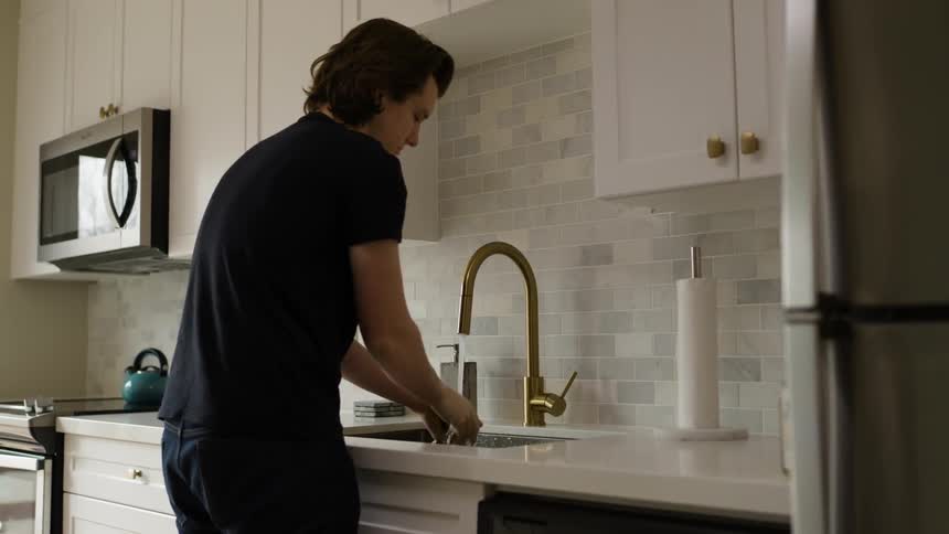 A man washes his hands at a kitchen sink