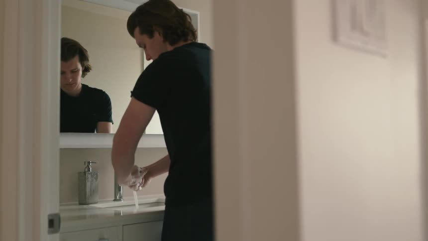A young man washes his hands in a bathroom
