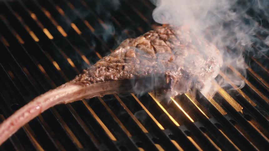 A cook throwing a steak onto a grill
