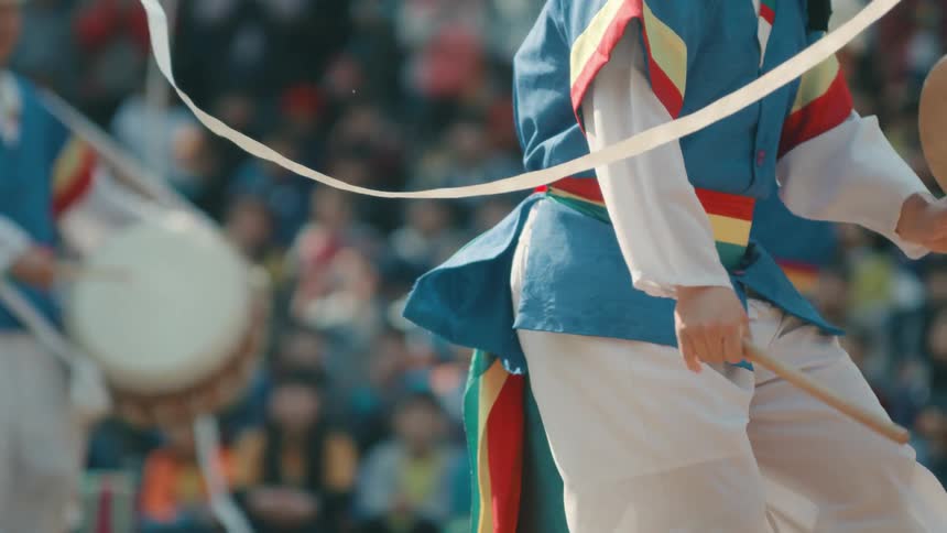 A group of people smack drums and wave streamers during a performance