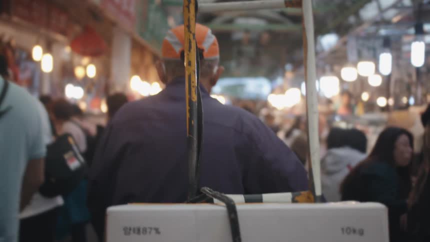 A man drags boxes through a marketplace