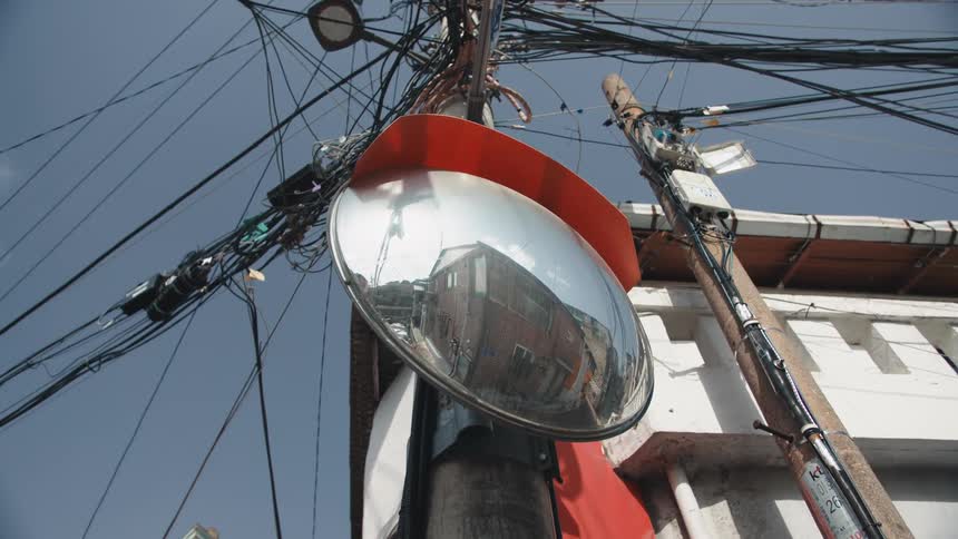 A street pole mirror reflects the building and road surrounding