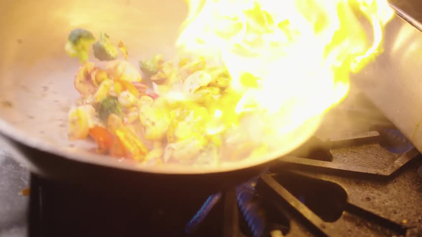 A chef cooks shrimp stir fry in a wok