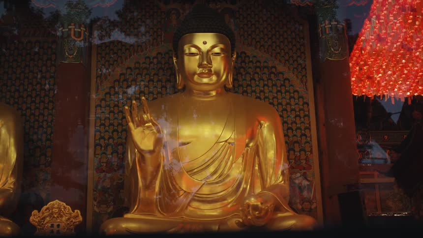 Golden buddha statue with ornate background and glass cover