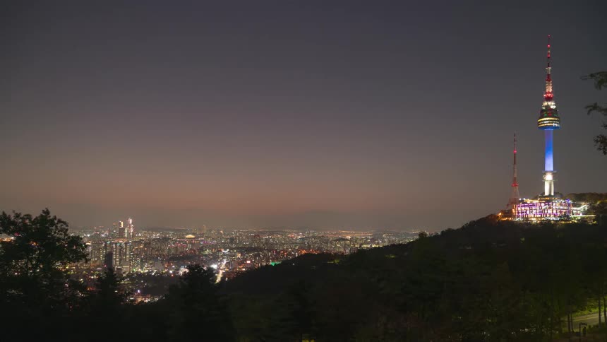 The tower on the hill is flashing at night