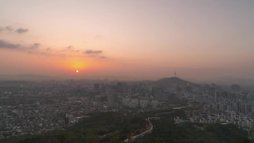 Clouds pass over a large city as the sun rises
