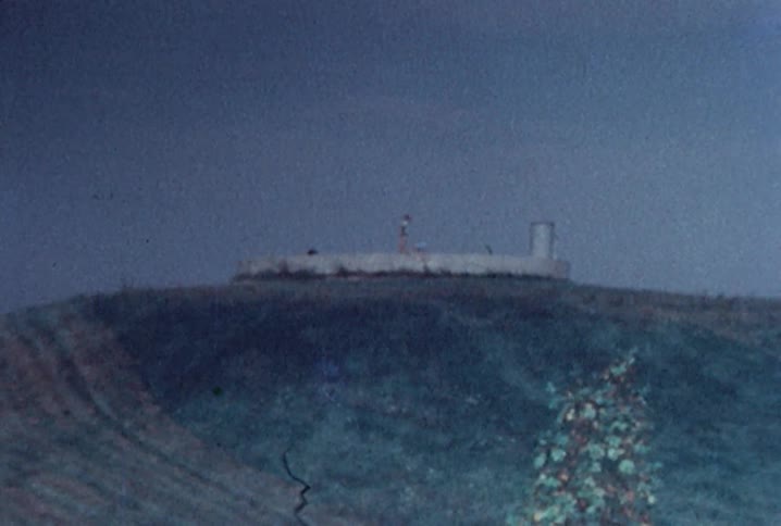 Wide shot of people climbing on to a short brick wall on top of a hill