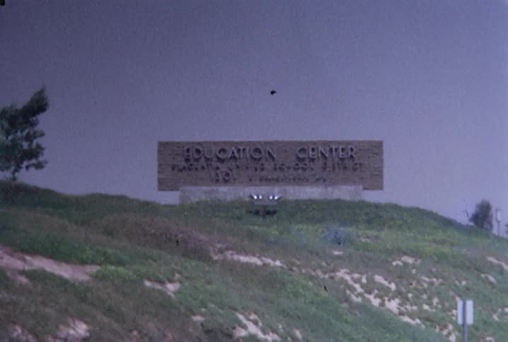 An education center sign on a green hill