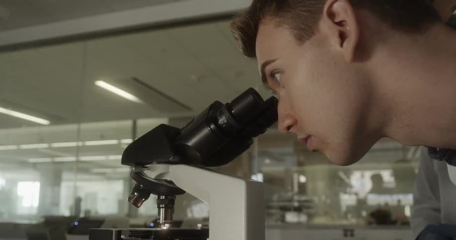 A man looks through a microscope