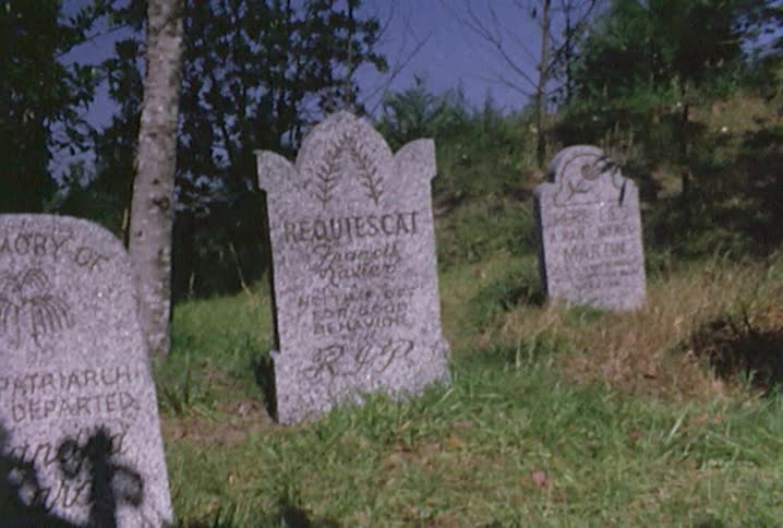 Three tombstones are surrounded by grass