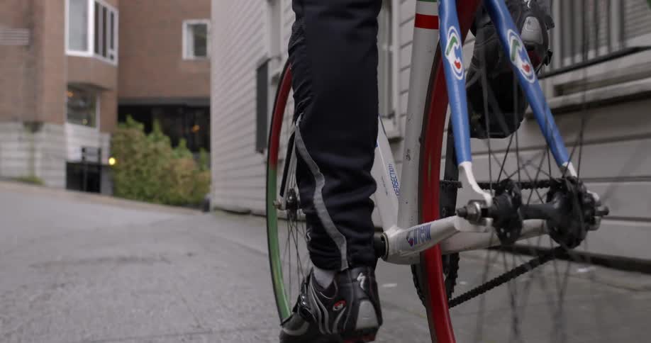 A person is riding a bicycle down an alley past homes