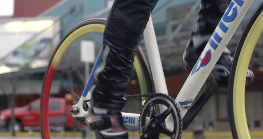 A man pedaling a bicycle down a city street as it rains