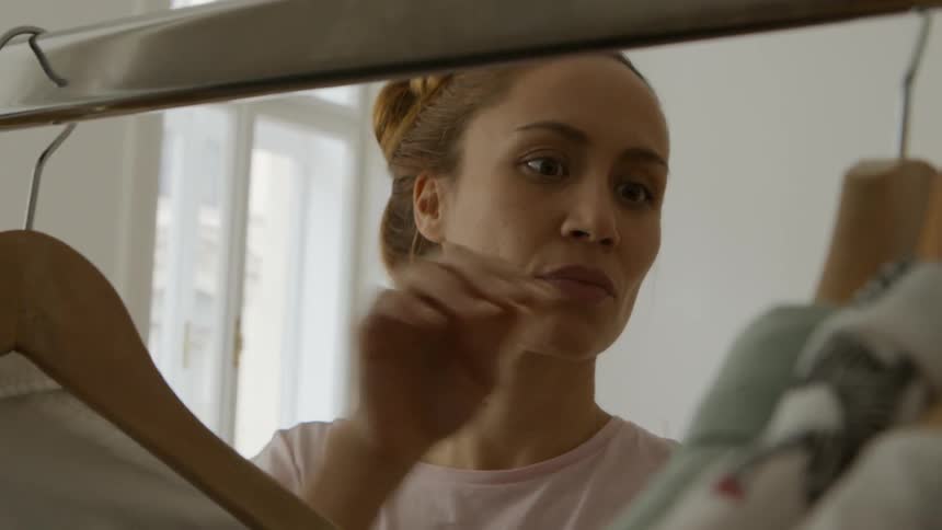 A woman is looking through her clothes