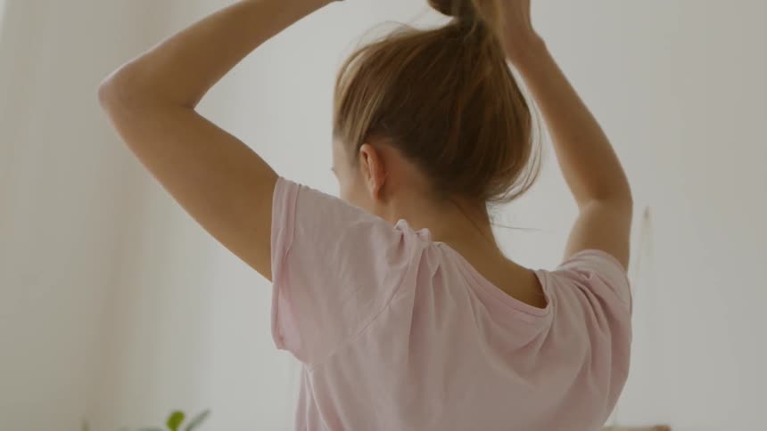 A woman untying her hair while sitting down in a room