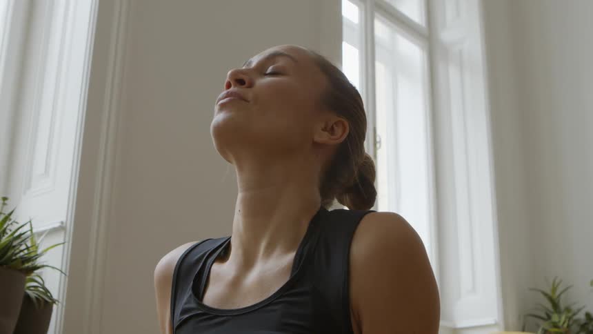 Woman performs yoga inside near window