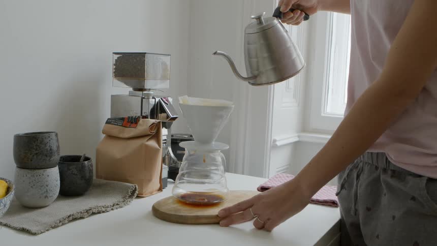 A woman pours hot water in to her coffee maker