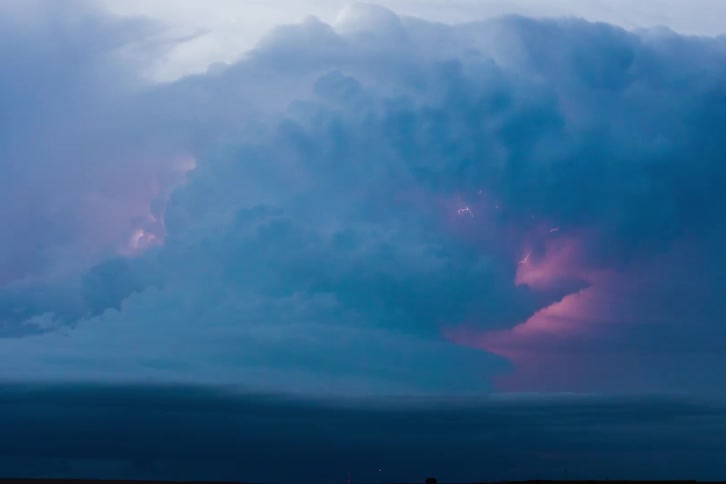 Lightning sparks and flashes in storm clouds moving over the ocean