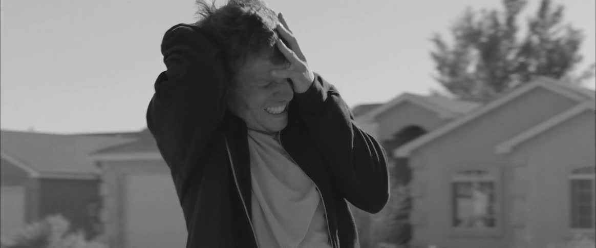 A man grabs his head while screaming and wincing in pain