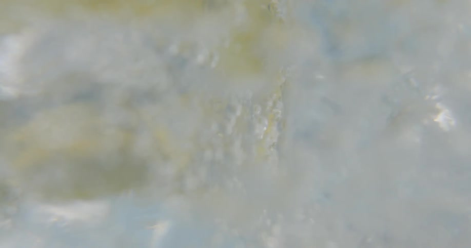 Sparkling water bubbling inside a glass filled with ice and a lemon slice