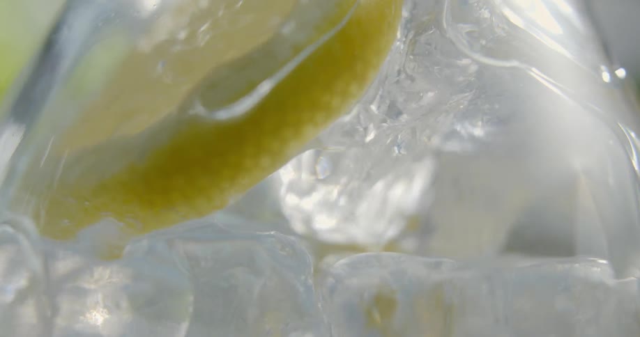 A lemon sits in a glass as water is poured in
