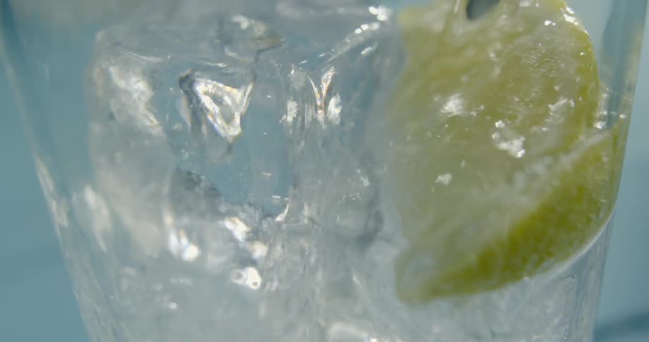 Ice and a lemon is in a glass that is filled with a drink