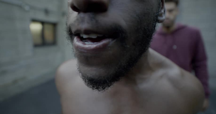 Black man talks angrily as two men stand behind him