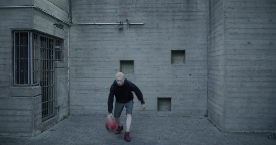 A man is bouncing the basketball in the yard